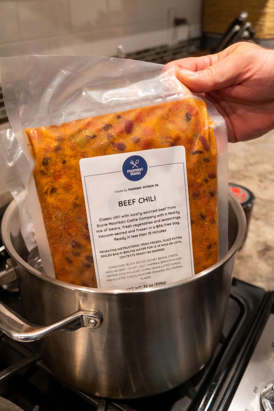 A vacuum sealed bag of Piedmont BBQ beef chili going into a pot of boiling water